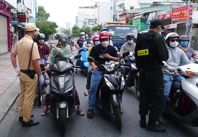 Cảnh sát kiểm tra giấy tờ người qua chốt đường Nơ Trang Long, quận Bình Thạnh, chiều 17/8. Ảnh: 